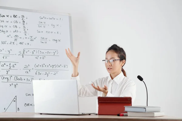 オンライン授業中の学生に三角数式を説明するテーブルの上にマイクを持つ若い先生 — ストック写真