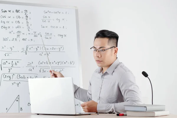 オンライン授業中に大学生にトピックを説明する際に数式をホワイトボードに指しているアジアの数学教師 — ストック写真