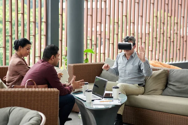 Investor watching virtual reality presentation of project when meeting with marketing team
