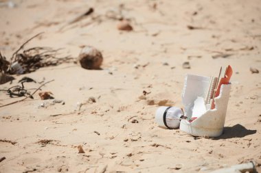 Kumlu sahilde bırakılan plastik çöpler, Dünya günü ve plaj temizleme konsepti