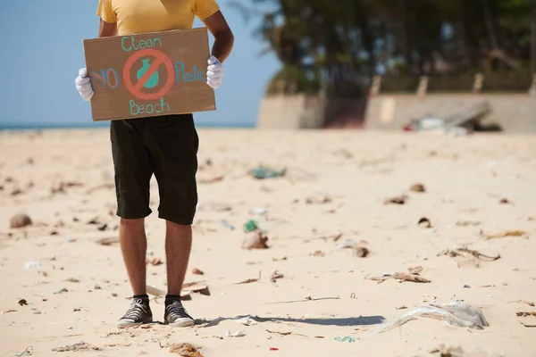 きれいなビーチとプラスチックのプラカードなしで汚れたビーチに立つ活動家の作物のイメージ — ストック写真