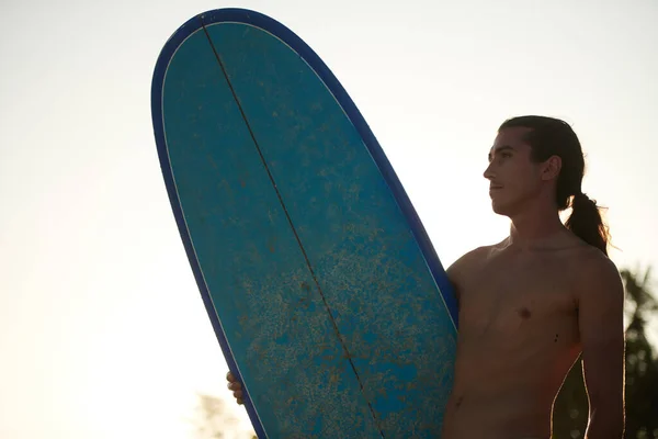 Pensive Mladý Surfař Dlouhými Vlasy Drží Surfovací Prkno Dívá Jinam — Stock fotografie