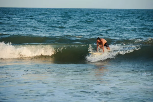 波をキャッチしようとして 日没時に海でサーフィン強い男をフィット — ストック写真