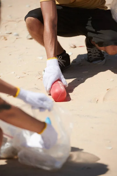 ボランティアのグループと海のビーチでプラスチックごみを拾う男の手 — ストック写真