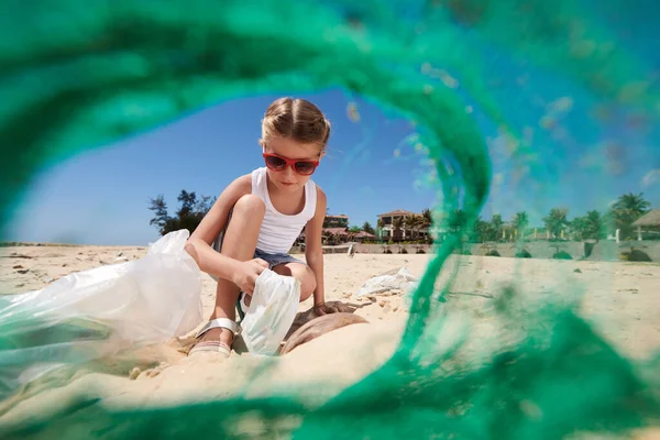 砂のビーチでゴミを収集サングラスの女の子 プラスチック製のネットを介して表示 — ストック写真