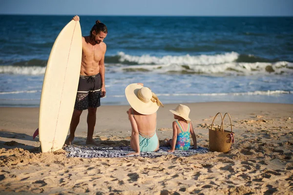 海でサーフィンした後 彼の妻と小さな娘に話して笑顔若い男 — ストック写真