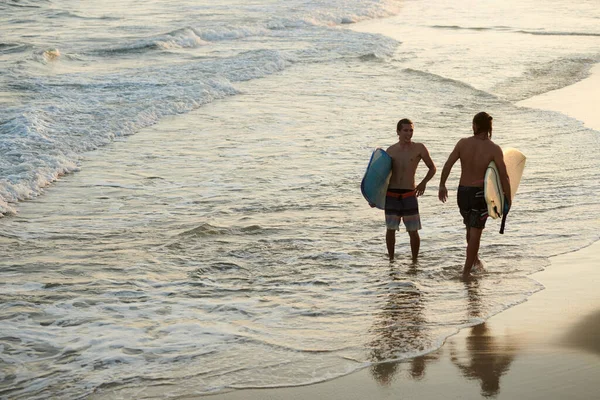快乐的男性朋友在日落前在海里冲浪 — 图库照片