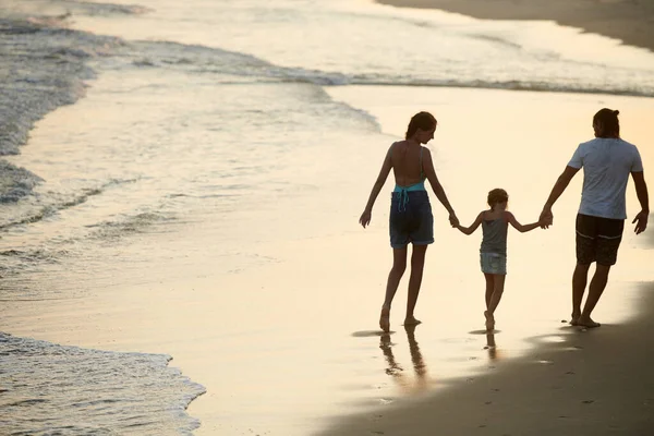 妈妈和爸爸牵着小女儿的手在海滩上散步 — 图库照片