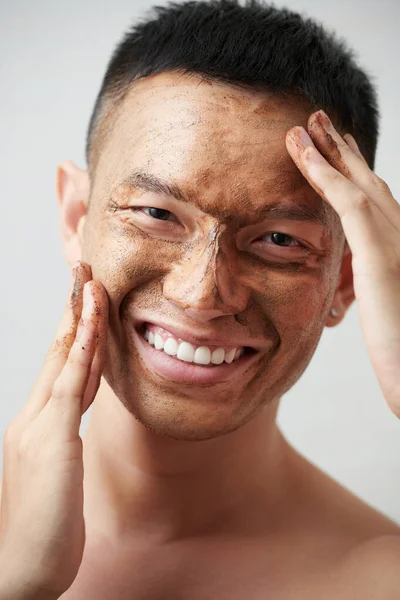 Positieve Aziatische Jonge Man Het Aanbrengen Van Koffie Scrub Gezicht — Stockfoto