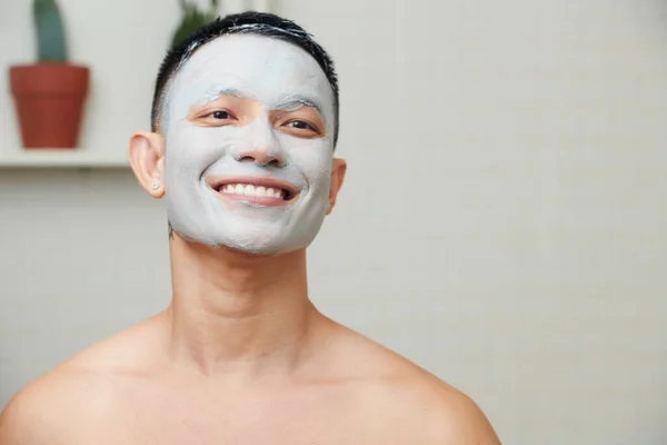 Cheerful Young Man Aging Clay Mask Face Looking Bathroom Mirror — Stock Photo, Image