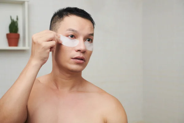 Gömleksiz Asyalı Genç Adam Banyoda Duruyor Göz Altı Bantlarını Parlatmaya — Stok fotoğraf