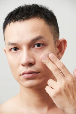 Ciddi bir gencin sabah rutininin bir parçası olarak nemlendirici losyon sürmesi.