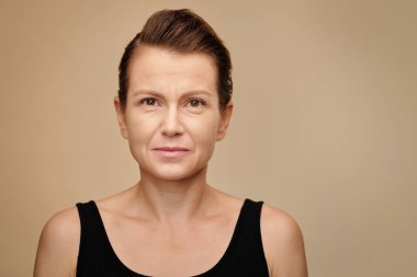 Kameraya bakan siyah elbiseli olgun kadının stüdyo portresi.