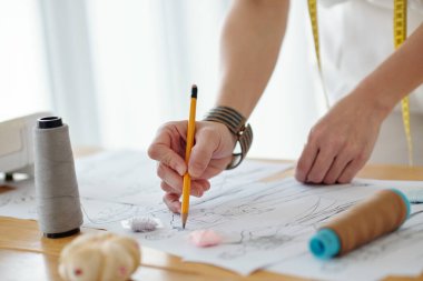 Yeni projeye başlamadan önce kadın terzinin elleri moda taslağı çiziyor.