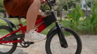 Korumalı kasklı küçük Asyalı bir çocuğun yaz günü bisiklet sürerken çekilmiş bir fotoğrafı.