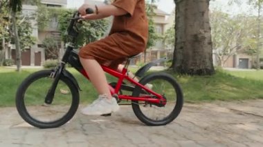 Yaz günü şehir caddesinde bisiklet sürerken küçük Asyalı çocuğu kameraya çek.