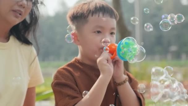 Счастливый Азиатский Ребенок Дует Мыльные Пузыри Улыбаясь Играя Ними Веселясь — стоковое видео