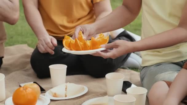 Наклоните Снимок Азиатки Делящейся Апельсиновыми Ломтиками Членами Семьи Наслаждаясь Фруктами — стоковое видео