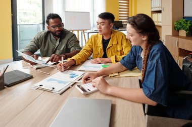 İş ekibi raporlarla çalışıyor, mali verileri analiz ediyor.