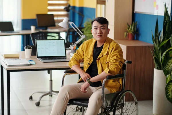 Portrait of young Asian man with disability working in modern office
