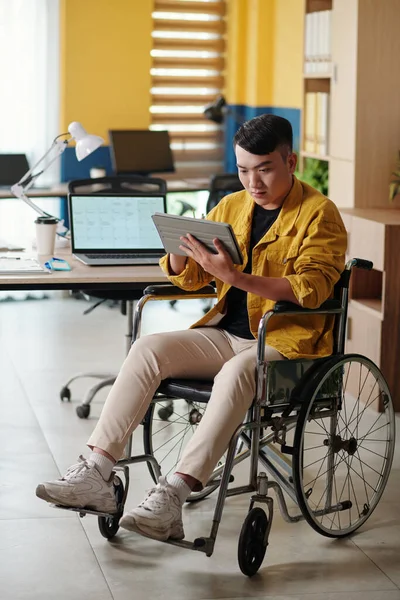 Młody Biznesmen Siedzący Wózku Inwalidzkim Czytający Raport Tablecie — Zdjęcie stockowe