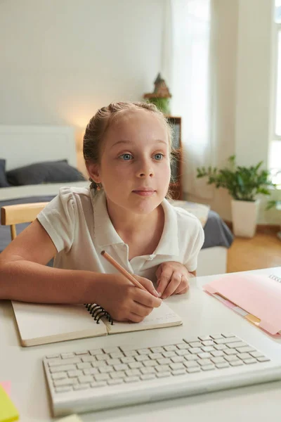 Schoolgirl watching educational video on computer with eyes wide open