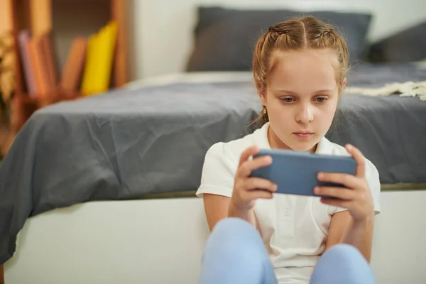 十多岁的女孩在智能手机上玩电子游戏 — 图库照片