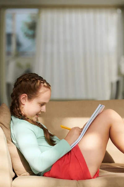 Sorrindo Menina Pré Adolescente Sentado Sofá Fazendo Lição Casa — Fotografia de Stock