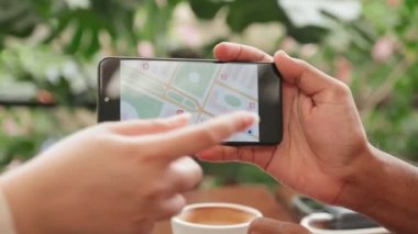 Tanımlanamayan erkek ve kadının ellerinde akıllı telefon olan ve haritayı ekranda tartışan yeşil bitkinin görüntülerini yakından çek.
