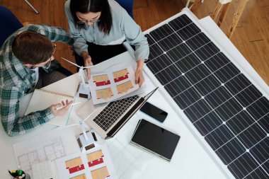 Yeşil enerji mühendisi müşterisine evi için kaç tane güneş paneline ihtiyacı olduğunu bulmasına yardım ediyor.