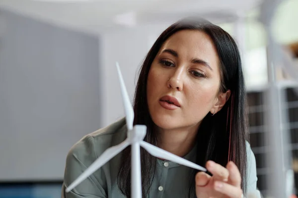 stock image Pensive woman looking closely at model of new innovative wind turbine