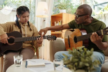 Genç kıza gitar tutmayı öğreten öğretmen.