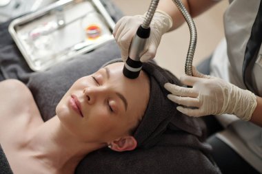 Kadın güzellik salonunda yaşlanma karşıtı prosedür uyguluyor, yukarıdan görünüyor.