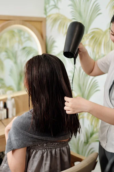 Mujer joven secar el cabello con secador de pelo y peinar el