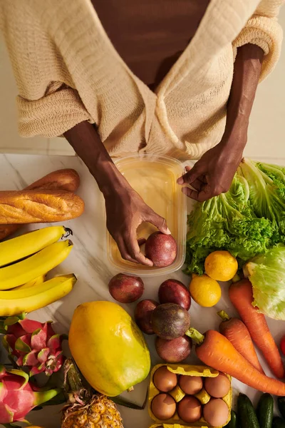 妇女将新鲜水果和蔬菜装在塑料容器中储存在冰箱中 — 图库照片