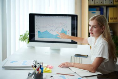 İş kadını meslektaşıyla konuşurken ekranı diyagramla işaret ediyor