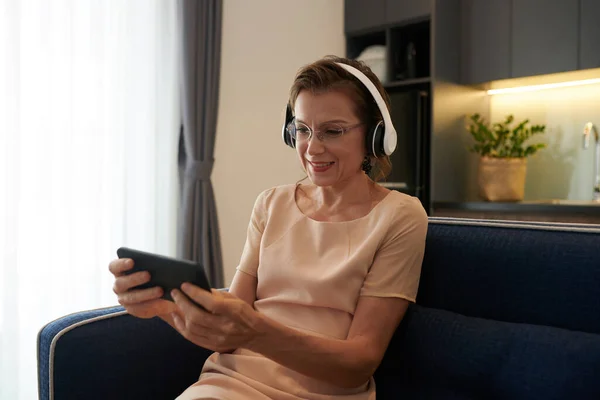 Podekscytowana Dojrzała Kobieta Nosi Słuchawki Podczas Gry Gry Wideo Smartfonie — Zdjęcie stockowe