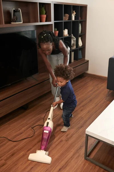 어머니가 처음으로 아들의 진공소제기를 청소하는 바닥을 조절하는 — 스톡 사진