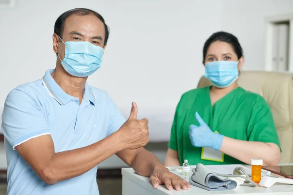 コロナウイルスから正常に回復した後 親指アップを示す医療用マスクのシニア男 — ストック写真