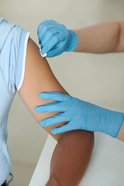 予防接種前に患者の腕を拭くためにアルコールで湿らせた綿棒を使用して看護師 — ストック写真