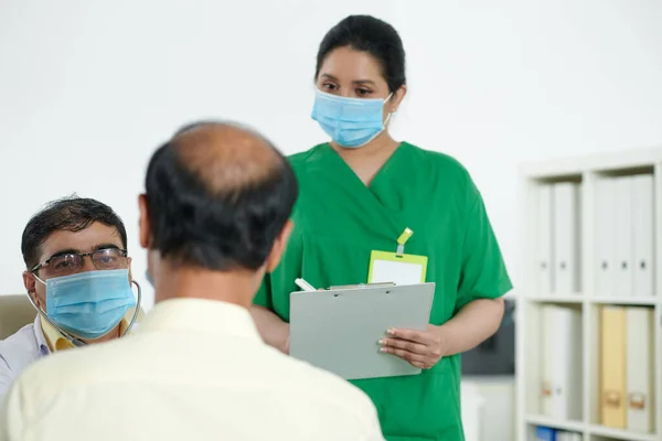 Ιατρική Νοσοκόμα Κρατώντας Σημειώσεις Στο Έγγραφο Ενώ Γιατρός Μιλάει Τον — Φωτογραφία Αρχείου