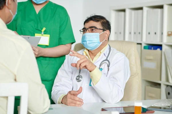 Σοβαρός Γενικός Ιατρός Ιατρική Μάσκα Μιλώντας Στον Ασθενή Και Εξηγώντας — Φωτογραφία Αρχείου