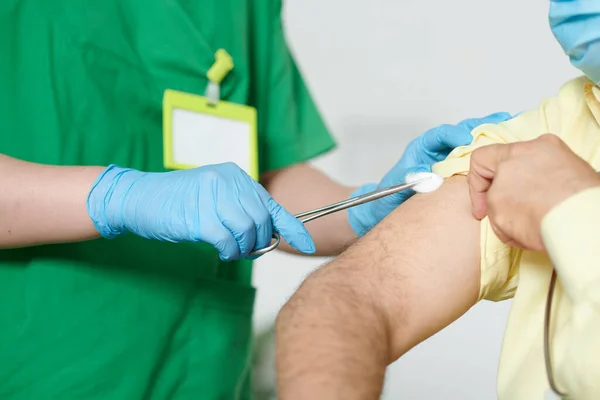 ゴム手袋で看護師のクローズアップ画像ワクチンを注射する前に綿球で患者の肩を拭く — ストック写真