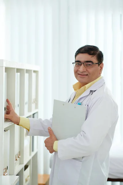 Gülümseyen Pratisyen Hekim Hastanedeki Arşivdeki Raftan Hastanın Tıbbi Geçmişini Alıyor — Stok fotoğraf
