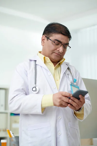 Ernsthafter Indischer Allgemeinmediziner Liest Sms Auf Smartphone — Stockfoto