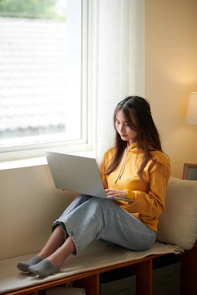 Pensive Mladý Vysokoškolák Sedí Lavičce Okně Bytu Pracuje Notebooku — Stock fotografie
