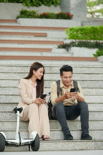 Usmívající Mladé Asijské Startuppers Sedí Schodech Testování Nové Mobilní Aplikace — Stock fotografie