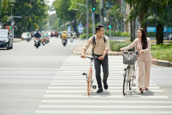 在人行横道上骑自行车横穿马路的年轻夫妇笑着 — 图库照片