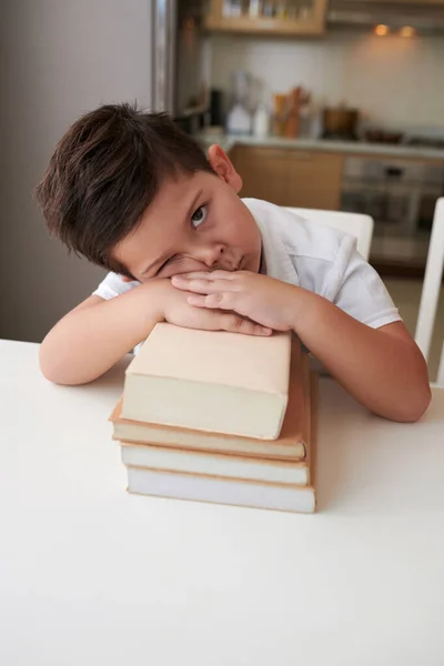 疲惫而无聊的小男孩靠在书架上或学校的书本上 看着相机 — 图库照片