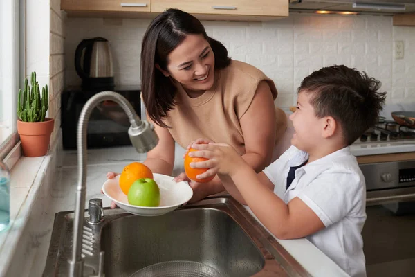 Ευτυχισμένη Μητέρα Κοιτάζοντας Ενθουσιασμένος Γιος Καθαρισμού Και Ξεφλούδισμα Πορτοκαλί Πάνω — Φωτογραφία Αρχείου